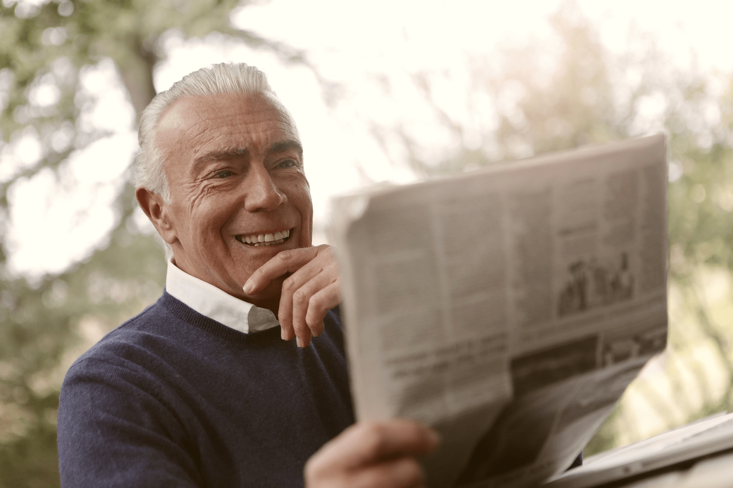 Man smiling reading the newspaper.